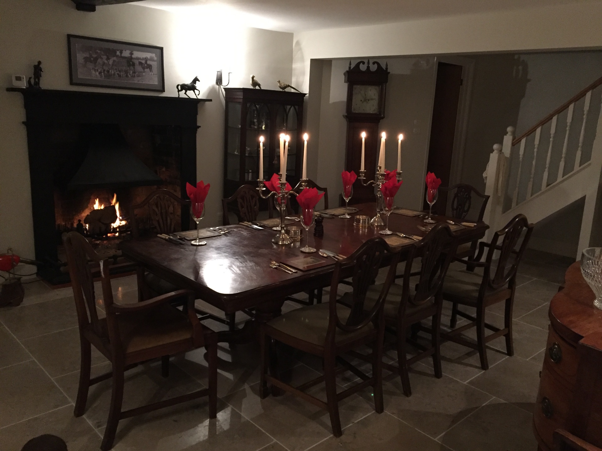 Candlelit dining table set for guests beside the roaring fire