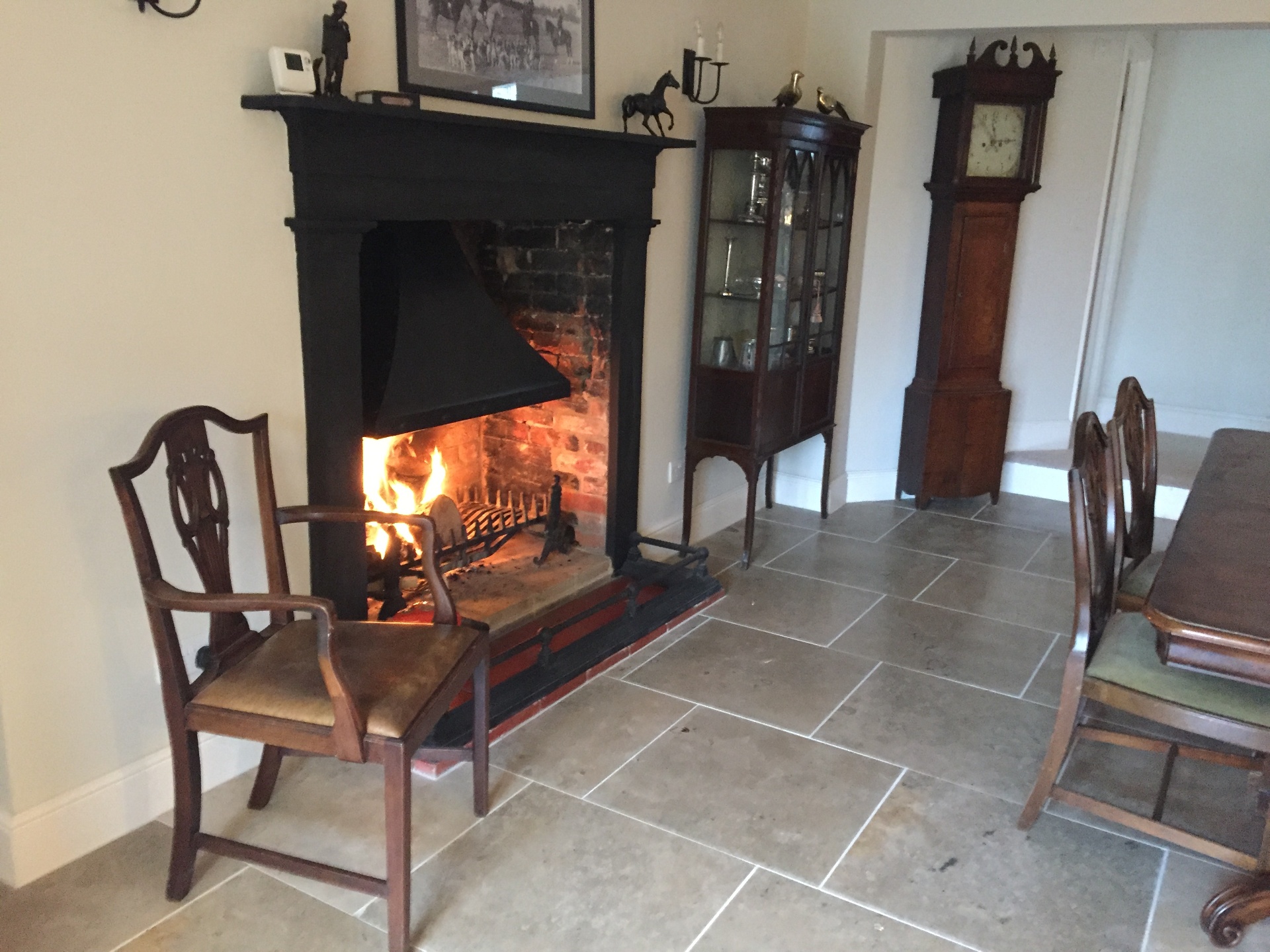 Open fire crackling in the dining room with antique chairs and grandfather clock