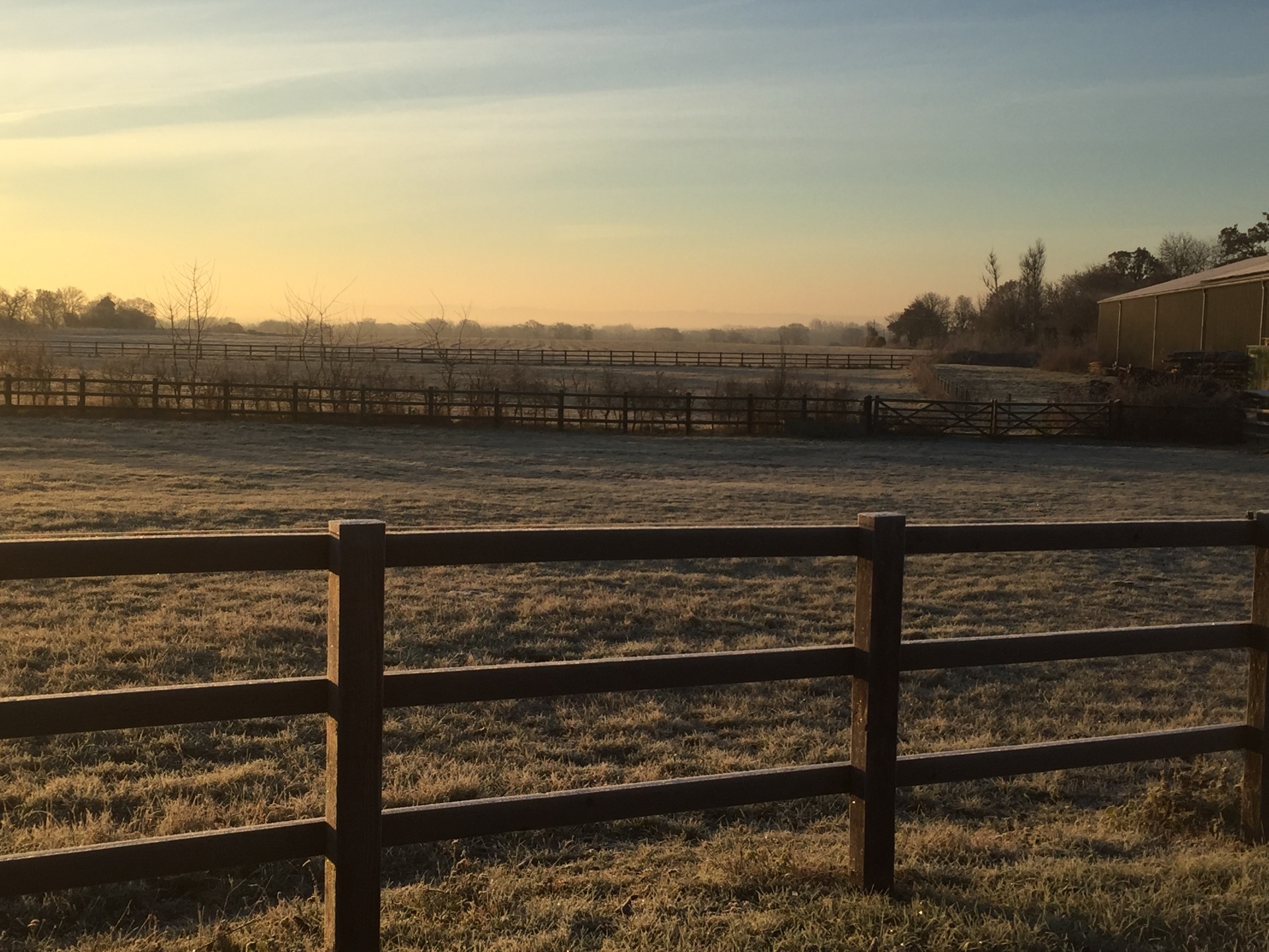 Frost-covered paddock and post-and-rail fencing at sunrise